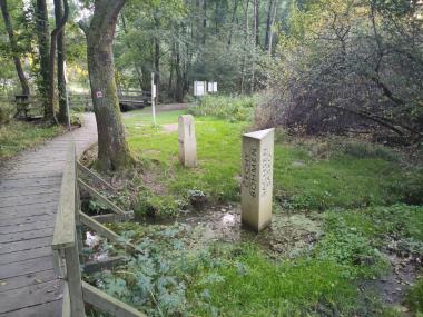 Dřevěný mostek přes hraniční potok s betonovými patníky na obou stranách