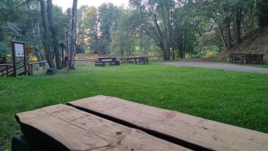 Zelená mýtina s lavičkami a dřevěným zábradlím