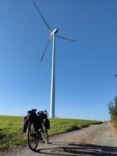 Pohled na větrnou elektrárnu na kopci, z cyklostezky, v popředí moje kolo