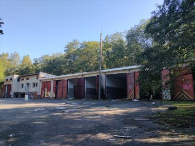 Řada garáží s otevřenými vraty a různé smetí poházené kolem